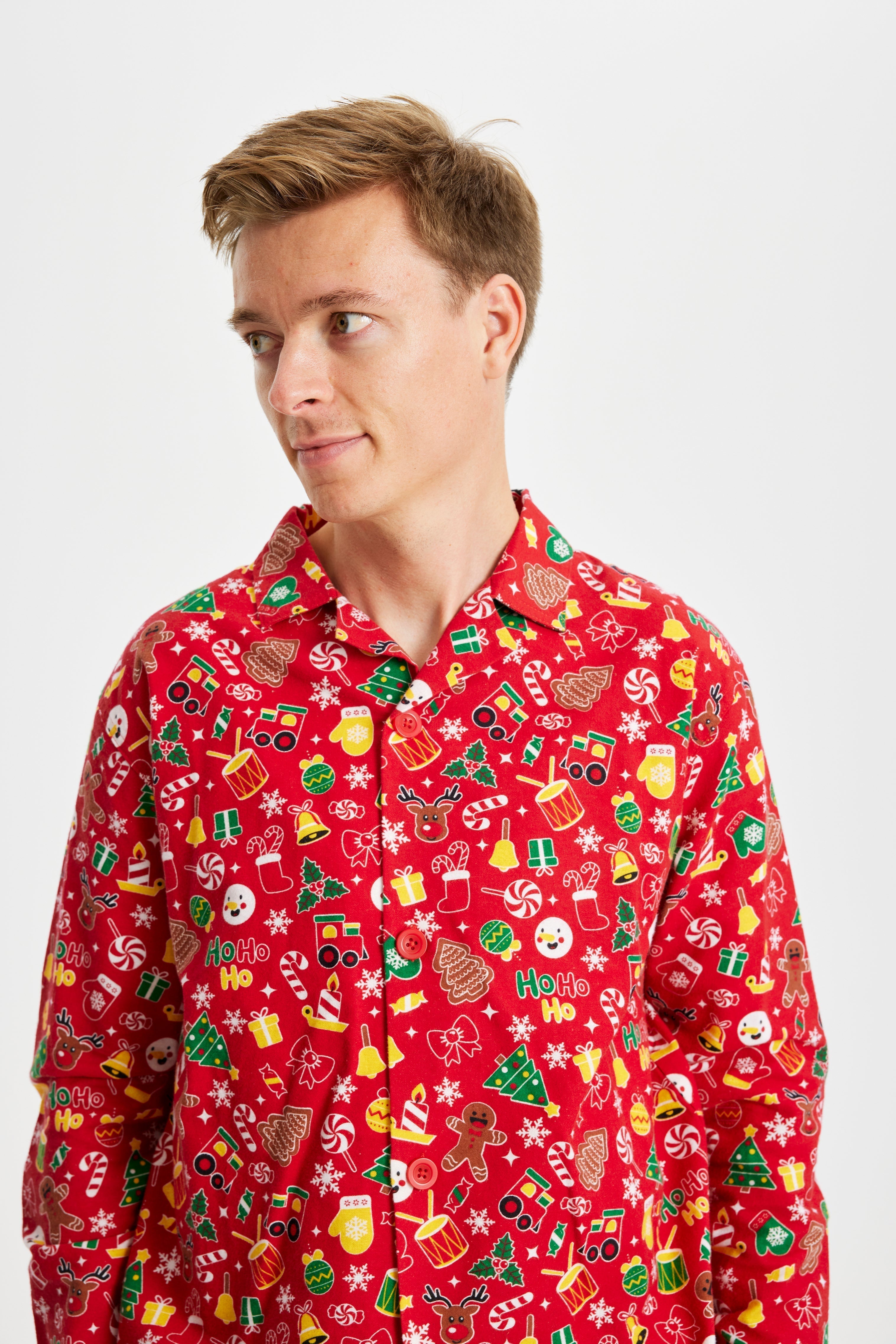 Un uomo che guarda di lato e indossa un pigiama natalizio rosso con stampa natalizia.